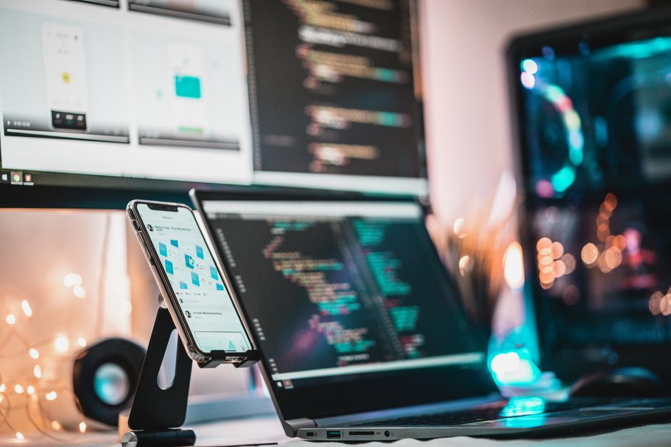 A close-up view of a tech setup with gadgets, coding screen, and smartphone, perfect for tech themes