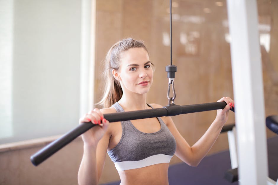 Young woman using gym equipment for strength training in a modern fitness facility.