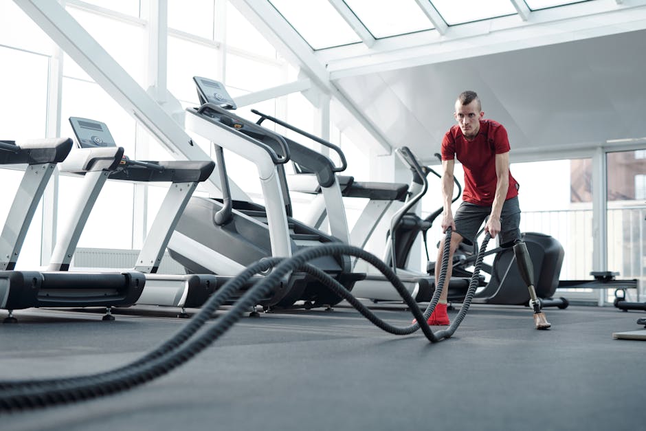 Young man with prosthetic leg working out in a modern gym with battle ropes, showcasing strength and determination