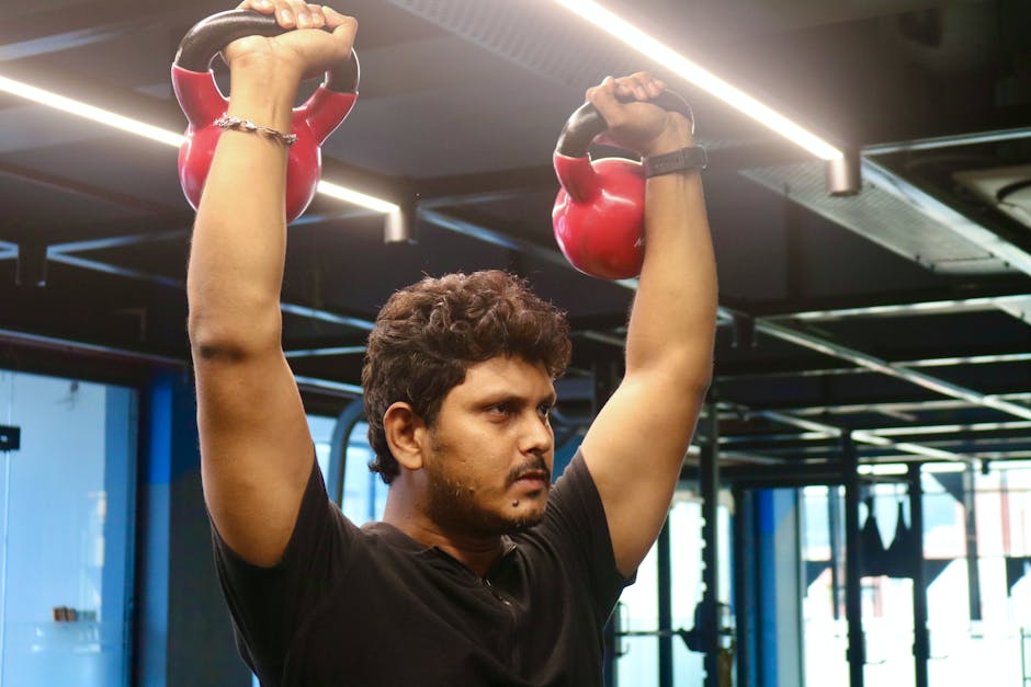 Focused man lifts kettlebells during an indoor workout session in a modern gym