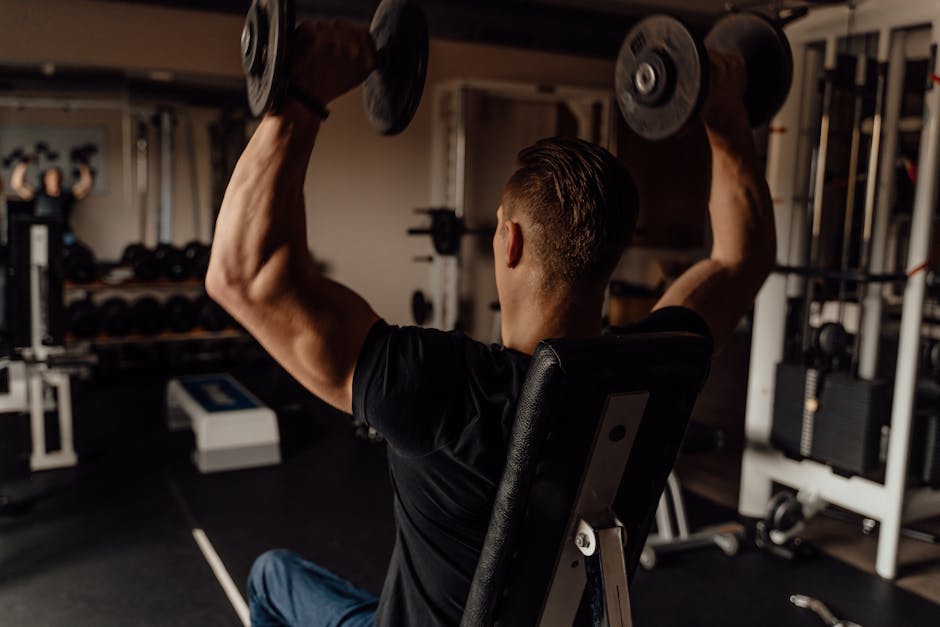 Adult man exercising with dumbbells in a gym, focused on fitness training