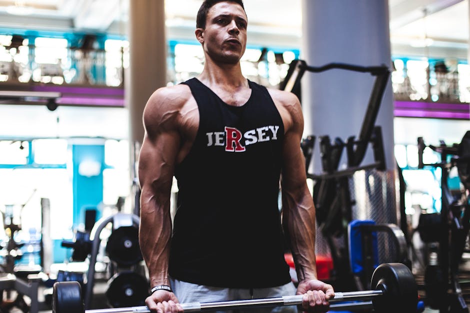 Fit man in a gym lifting barbell, showcasing strength and fitness in activewear.